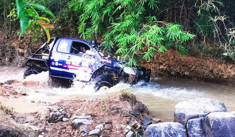 Một xe đua đang vượt suối đá.