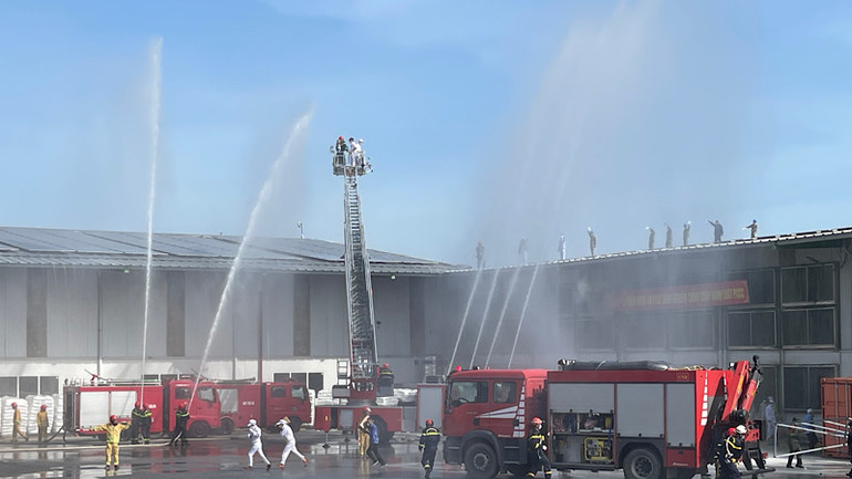 Các xe chữa cháy phun nước mái nhà xưởng đang xảy ra vụ cháy.