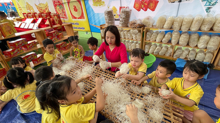 Cô giáo mầm non hướng dẫn trẻ kỹ năng cuộn bánh đa gạo.