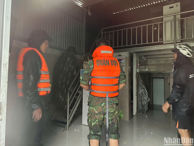 Lực lượng chức năng đến từng nhà để hỗ trợ người dân di dời đồ đạc lên cao và đưa người ra khỏi khu vực ngập lũ. (Ảnh: CÔNG VINH)