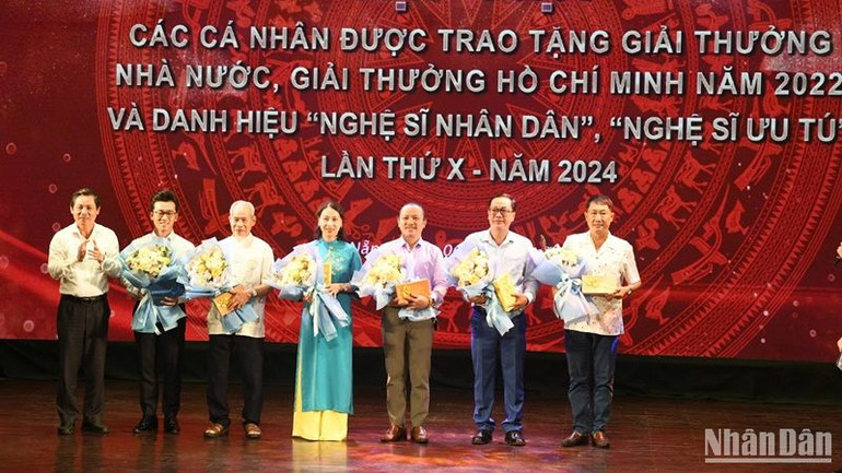 Ông Phạm Tấn Xử, Giám đốc Sở Văn hóa và Thể thao thành phố Đà Nẵng tặng hoa chúc mừng các nghệ sỹ được phong tặng danh hiệu Nghệ sỹ ưu tú. (Ảnh: ANH ĐÀO)