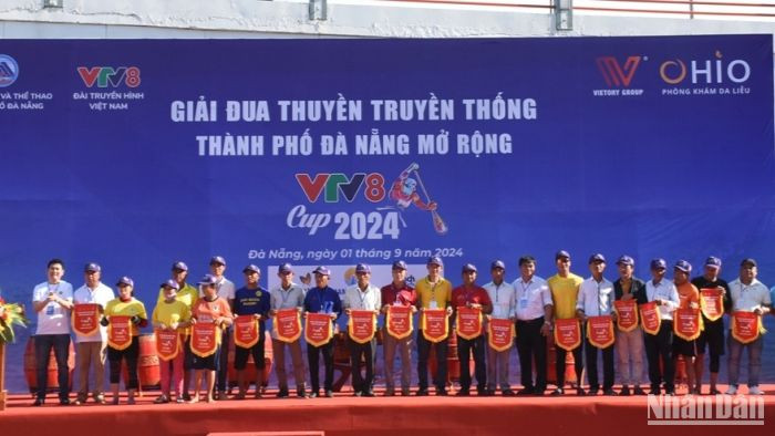 Ban tổ chức trao cờ lưu niệm cho các đội tham gia đua thuyền. (Ảnh: ANH ĐÀO)