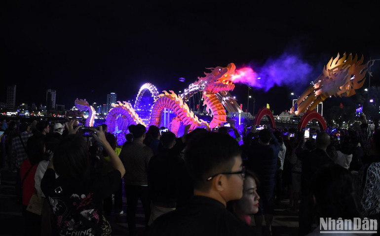 Rất nhiều người dân thích thú với hình ảnh linh vật rồng phun khói trong đêm giao thừa. (Ảnh: ANH ĐÀO)