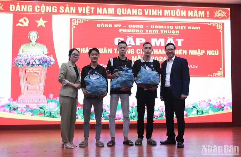 Đồng chí Lại Tiến Hương, Bí thư Đảng ủy phường Tam Thuận và đồng chí Hồ Đàm Như Nga, Chủ tịch Ủy ban nhân dân phường Tam Thuận, trao quân trang cho 3 tân binh Hiền Nhân, Hiền Nhơn và Hiền Phúc. Ảnh: ANH ĐÀO