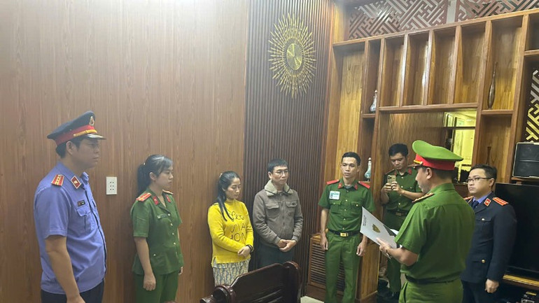 Cơ quan chức năng tống đạt quyết định khởi tố bị can, bắt tạm giam, cấm đi khỏi nơi cư trú đối với vợ chồng ông Phạm Xu Tý. (Ảnh: Công an cung cấp)