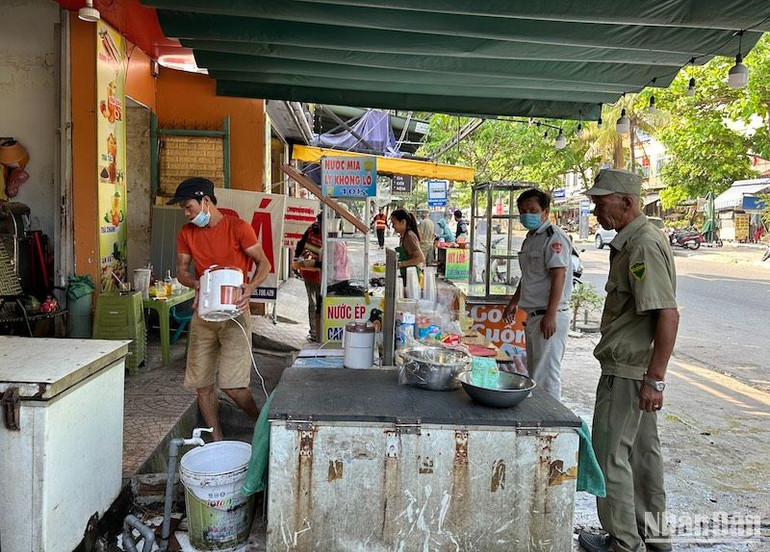 Lực lượng quy tắc đô thị phường Nại Hiên Đông tuyên truyền, vận động người dân thu dọn vật dụng kinh doanh, để tiến hành kẻ vạch vỉa hè. Ảnh: ANH ĐÀO