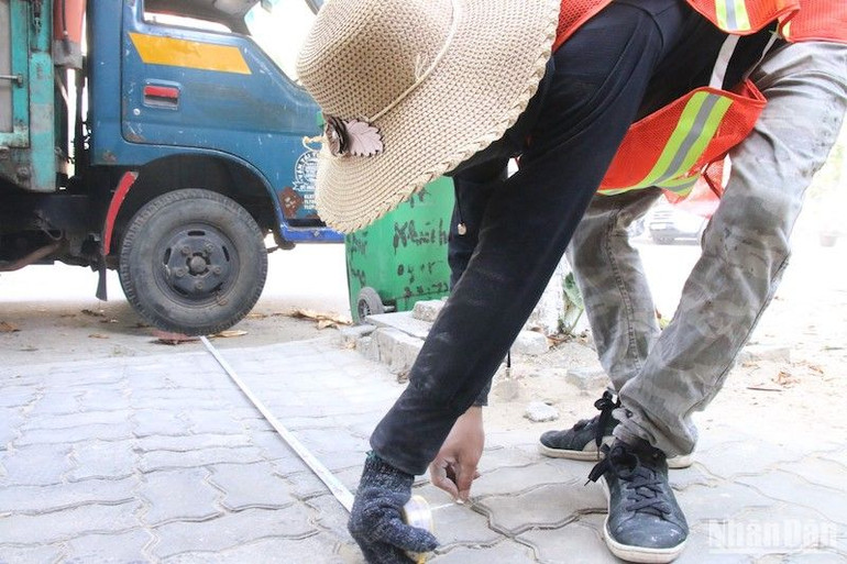 Đo diện tích vỉa hè trước khi kẻ sơn. Ảnh: ANH ĐÀO