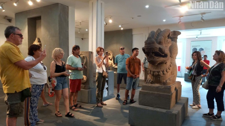 Du khách tham quan Bảo vật Quốc gia Tượng Rồng Tháp Mẫm tại Bảo tàng Điêu khắc Chăm. (Ảnh: ANH ĐÀO)