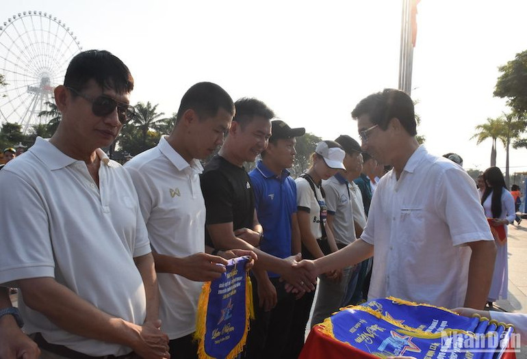 Phó Chủ tịch Ủy ban nhân dân TP Đà Nẵng Trần Chí Cường tặng cờ lưu niệm cho các đơn vị tham gia Giải Việt dã - chạy Vũ trang truyền thống Báo Đà Nẵng lần thứ 27. (Ảnh: ANH ĐÀO)