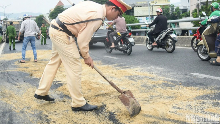 Lực lượng chức năng rải cát xuống khu vực dầu nhớt của xe tải bị nạn đổ loang, để hạn chế các phương tiện trơn trượt gây nguy hiểm. (Ảnh: ANH ĐÀO)