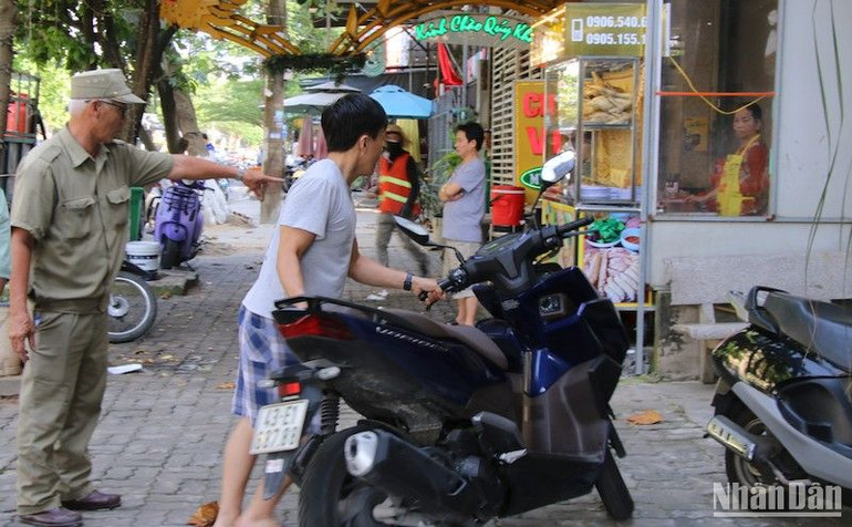 Hướng dẫn người dân dựng xe máy theo vạch đường quy định. Ảnh: ANH ĐÀO
