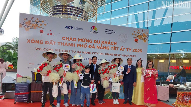 Những hành khách quốc tế đến Đà Nẵng bằng đường hàng không đón nhận quà và chụp ảnh lưu niệm cùng đại diện Sở Du lịch thành phố Đà Nẵng. (Ảnh: ANH ĐÀO)