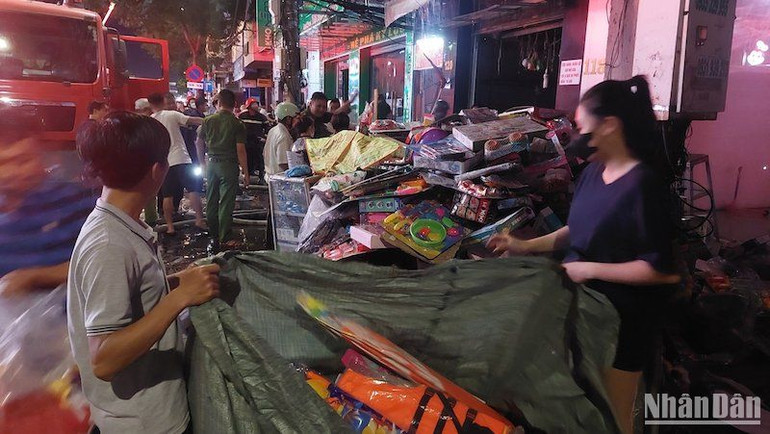 Người dân giúp chủ cửa hàng mang hàng hóa ra ngoài, tránh ngọn lửa lan rộng.