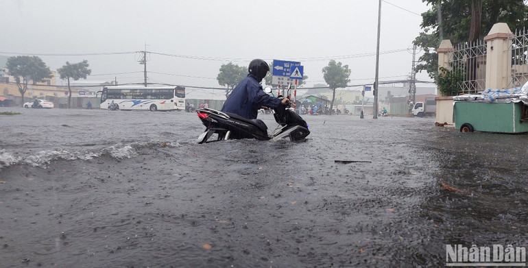 Người dân dắt xe máy qua khu vực ngập sâu.
