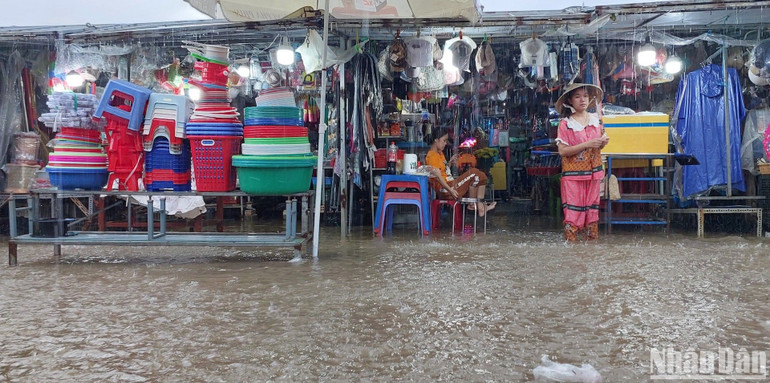 Tiểu thương chợ Thanh Vinh lội bì bõm trong nước ngập sâu để kê cao hàng hóa.