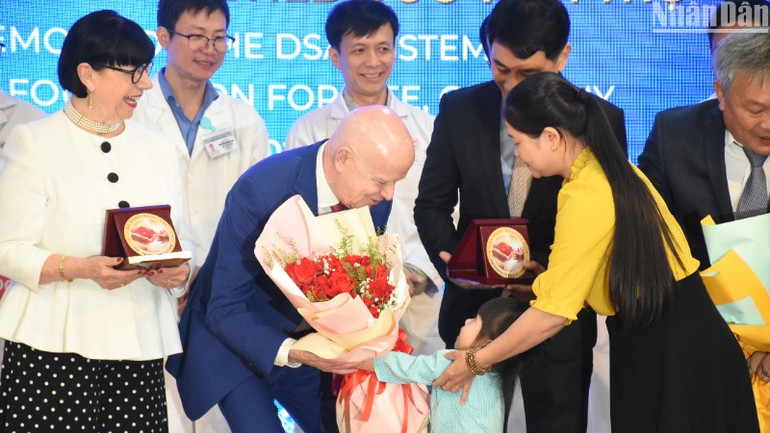 Hình ảnh xúc động tại chương trình khi một bệnh nhân nhỏ tặng hoa cảm ơn Giáo sư Erich Johann Lejeune. Em sẽ được tổ chức "Trái tim vì trái tim" hỗ trợ mổ tim trong vài ngày tới. (Ảnh: ANH ĐÀO)