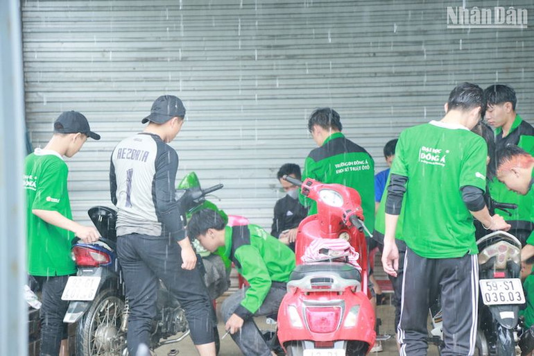 Hình ảnh các bạn sinh viên dầm mưa sữa xe máy miễn phí cho người dân vùng ngập lũ. Ảnh: ANH ĐÀO