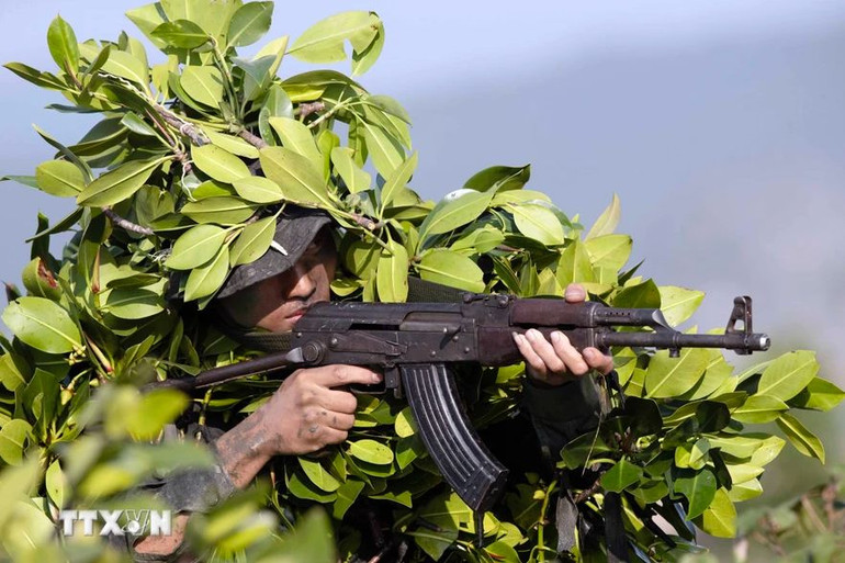 Chiến sĩ Cảnh sát cơ động thực hiện bài huấn luyện dùng cây cối chung quanh để nguỵ trang. (Ảnh: TTXVN)