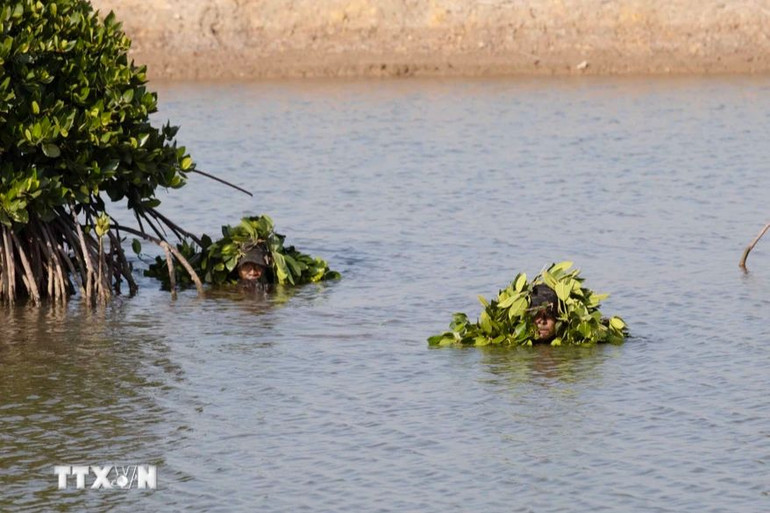 Chiến sĩ Cảnh sát cơ động thực hiện bài tập nguỵ trang dưới nước tiếp cận mục tiêu. (Ảnh: TTXVN)