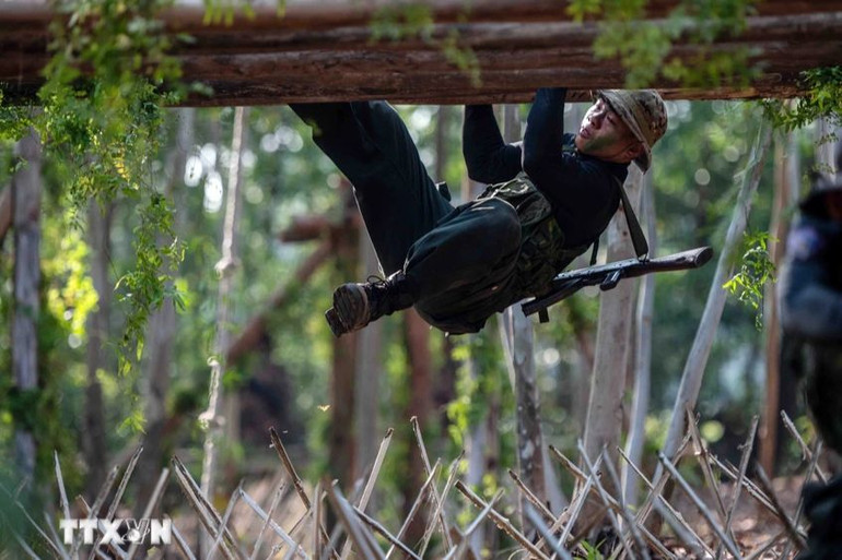 Thực hiện bài tập đu người trên các thanh gỗ để vượt qua hàng trăm cọc tre vót nhọn đầu ở phía dưới. (Ảnh: TTXVN)