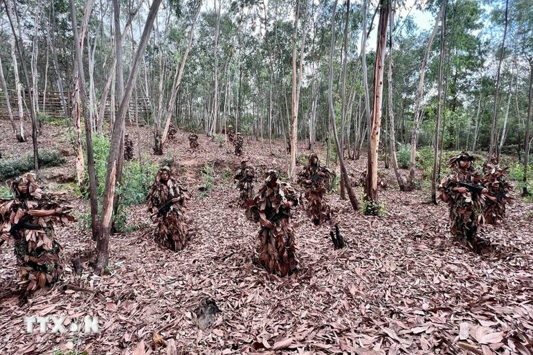 Chiến sĩ Cảnh sát cơ động chống khủng bố thực hiện bài tập nguỵ trang dưới lớp lá khô, tiếp cận đối tượng một khoảng cách gần nhất mà không bị phát hiện. (Ảnh: TTXVN)