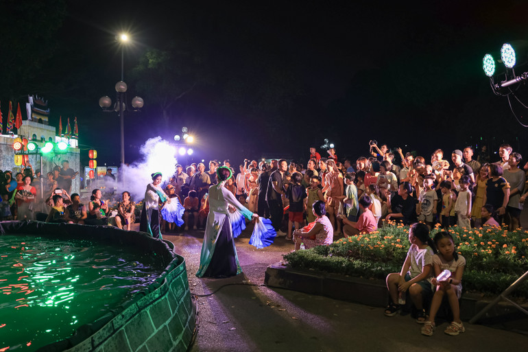 Người dân thích thú trước tiết mục biểu diễn nghệ thuật múa rối nước.