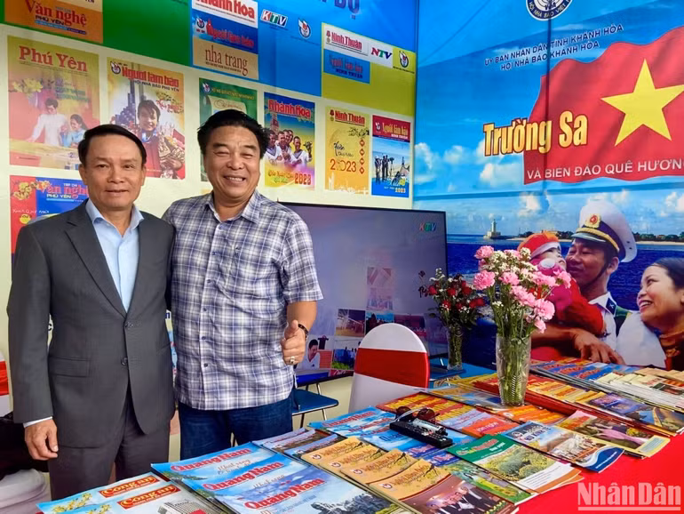 Ông Đoàn Minh Long (bên phải) cùng Phó Chủ tịch Thường trực Hội Nhà báo Việt Nam Nguyễn Đức Lợi tại gian hàng của Hội Nhà báo các tỉnh, thành phố Trung - Nam Trung Bộ. (Ảnh: NGỌC KHÁNH)