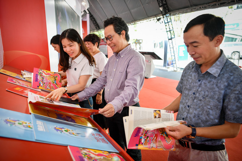 Nhà báo Vũ Mai Hoàng cùng các đại biểu tại gian trưng bày của Báo Nhân Dân.