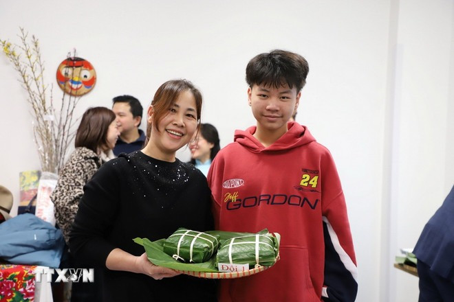 Đội tham gia hội thi gói bánh chưng hạnh phúc với sản phẩm của mình. (Ảnh: TTXVN)