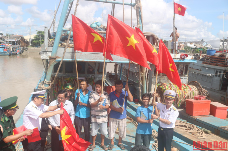 Cán bộ, chiến sĩ Vùng 2 Hải quân tặng cờ Tổ quốc cho các chủ phương tiện tàu cá đánh bắt xa bờ tại thị trấn Định An, huyện Trà Cú, tỉnh Trà Vinh.
