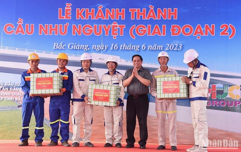 Thủ tướng Phạm Minh Chính trao tặng quà cho công nhân tham gia xây dựng cầu. (Ảnh: TRẦN HẢI)
