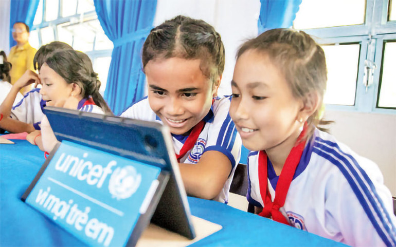 Diễm Như (trái) và các bạn lần đầu trải nghiệm thư viện số trên máy tính bảng. Ảnh: UNICEF Việt Nam\Trương Việt Hùng