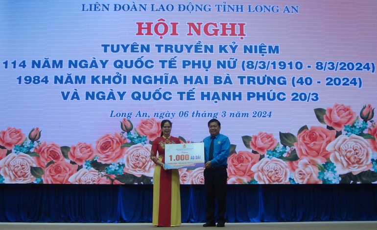 Chủ tịch Liên đoàn Lao động Long An Nguyễn Văn Quí trao bảng tượng trưng 1.000 áo dài cho công nhân viên chức lao động có hoàn cảnh khó khăn.