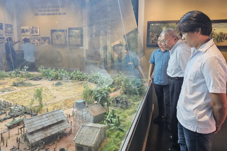 Nhà điêu khắc Võ Công Chiến (đứng giữa) tham quan mô hình Vành đai diệt Mỹ Rạch Kiến tại khu Di tích Ngã tư Rạch Kiến.