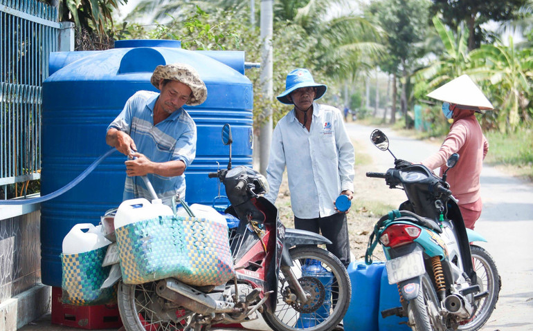 Người dân xã Đức Tân (hyện Tân Trụ) tranh thủ lấy nước do Công ty Công trình đô thị Long An chở nước hợp vệ sinh hỗ trợ mỗi ngày.