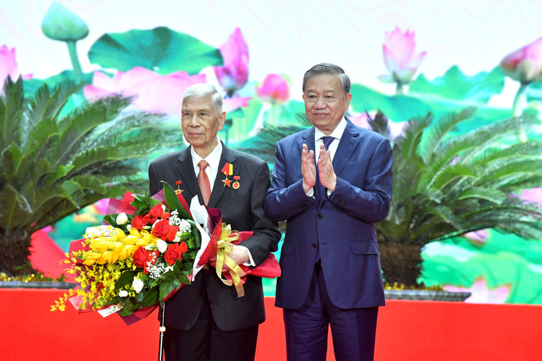 Tổng Bí thư Tô Lâm trao Huy hiệu 80 năm tuổi Đảng và tặng hoa chúc mừng đồng chí Đặng Quân Thụy. (Ảnh: ĐĂNG KHOA)