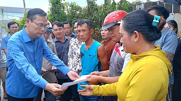 Bí thư Huyện ủy Năm Căn (tỉnh Cà Mau) Lượng Trọng Quyền (bìa trái) trao hỗ trợ bước đầu cho các hộ dân có nhà bị ảnh hưởng bởi vụ cháy.