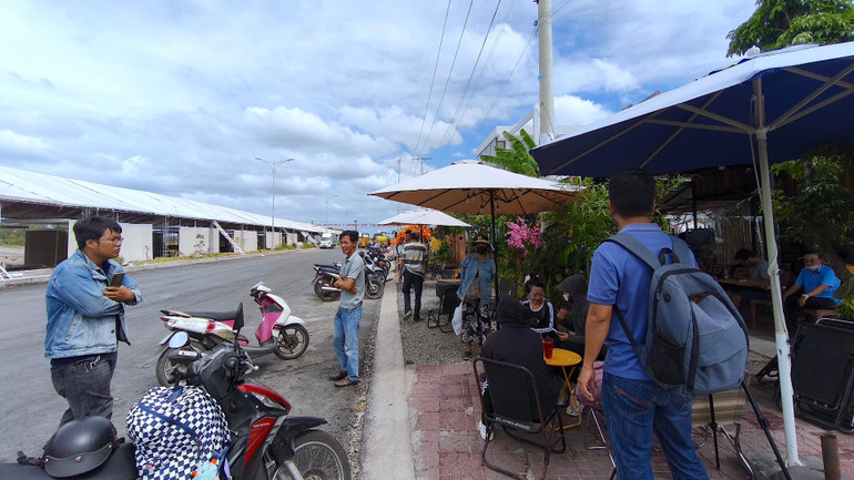 Một nhóm tiểu thương đến từ nhiều tỉnh, thành phố khác nhau tham gia hoạt động hội chợ tại miền biển Sông Đốc tụ tập cà phê “đốt thời gian” vì chưa được đưa hàng vào trong.