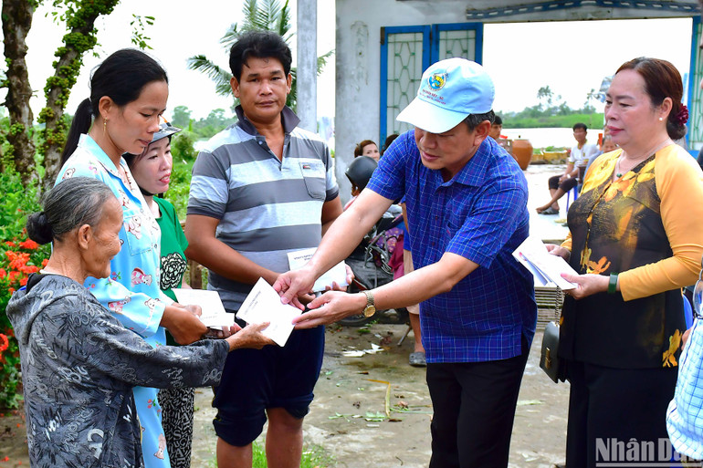 Phó Chủ tịch Mặt trận Tổ quốc tỉnh Cà Mau (đội nón) trao hỗ trợ bước đầu cho hộ dân huyện U Minh có nhà bị hư hỏng do dông lốc.