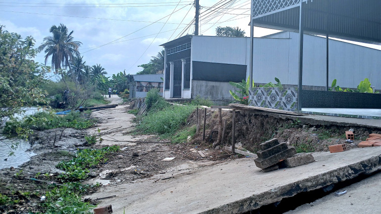 Đoạn lộ trước nhà bà Huyền bị sụp xuống sông, việc kinh doanh nước giải khát ế ẩm vì lộ hư, ít người qua lại.
