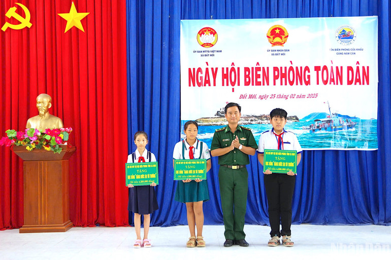 Thiếu tá Lâm Huy Vũ, Chính trị viên Đồn Biên phòng Cửa khẩu cảng Năm Căn tặng học bổng cho các em học sinh trong chương trình “Nâng bước em đến trường” do đơn vị nhận đỡ đầu.