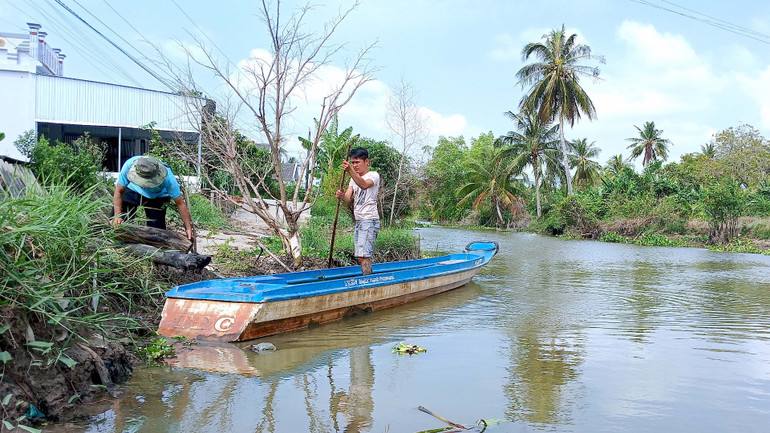 Người dân dọc tuyến Kênh Quảng Hảo dùng xuồng di chuyển sang bờ đối diện để đi tiếp bằng xe gắn máy mỗi khi có chuyện cần.