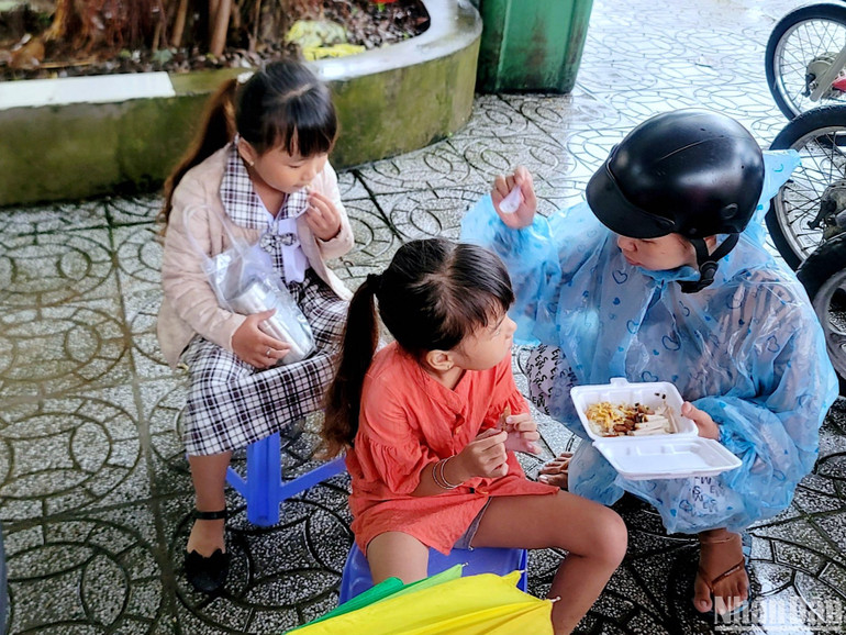 Một phụ huynh tại thành phố Cà Mau tranh thủ cho con ăn sáng ngay tại sân trường để kịp giờ khai giảng năm học mới.