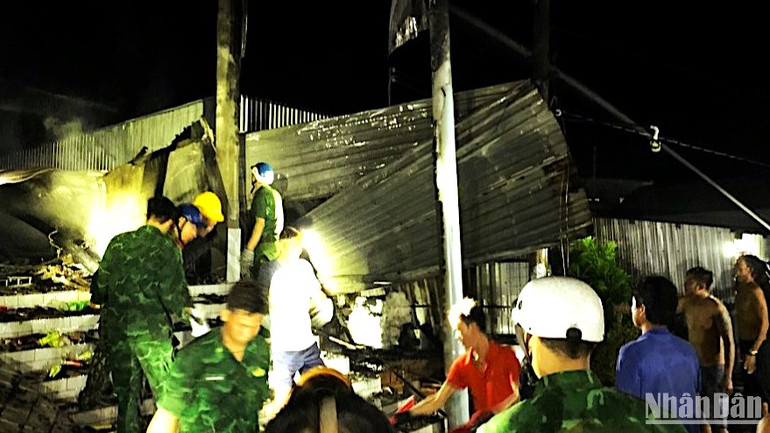Lực lượng chức năng địa phương hỗ trợ dân thu dọn đồ đạc, khắc phục thiệt hại sau vụ cháy vào rạng sáng 15/5.