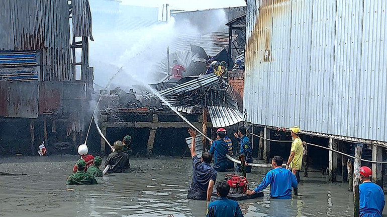 Lực lượng chức năng huyện Năm Căn nỗ lực dập lửa khu vực cháy nhà nằm cặp mé sông vào sáng 28/3.