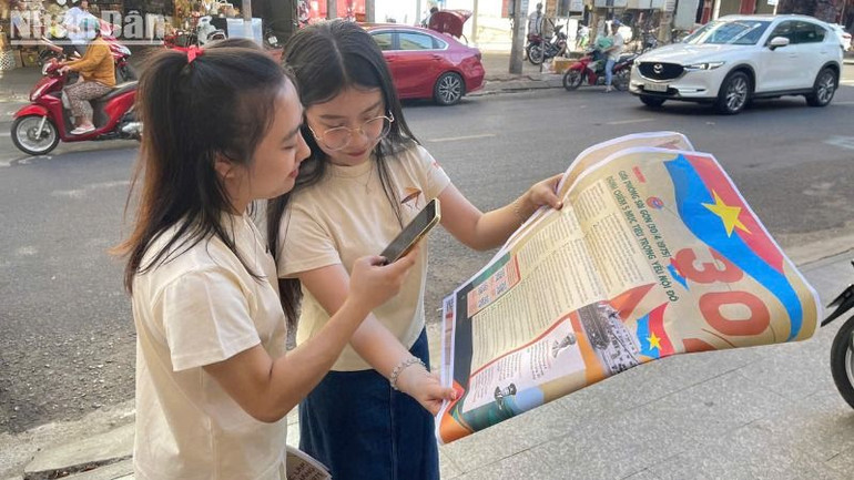 Các bạn trẻ trải nghiệm quét 4 mã QR để xem video động trên phụ san với công nghệ AR.