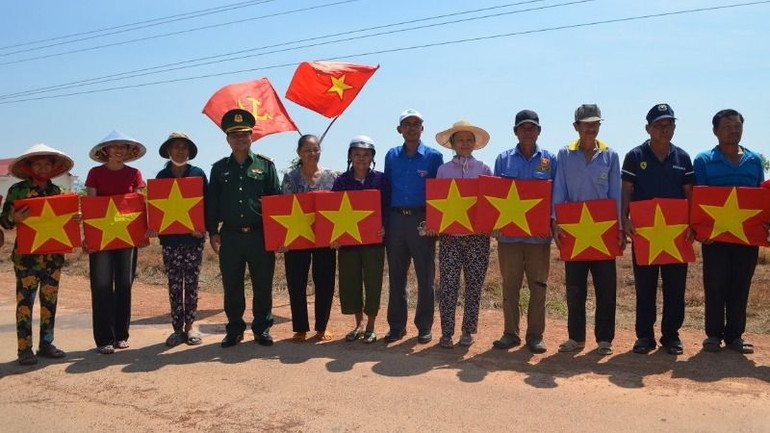 Đại diện lãnh đạo Bộ Chỉ huy Bộ đội Biên phòng tỉnh Đắk Lắk và Tỉnh đoàn Lâm Đồng tặng cờ Tổ quốc cho bà con nhân dân khu vực biên giới.