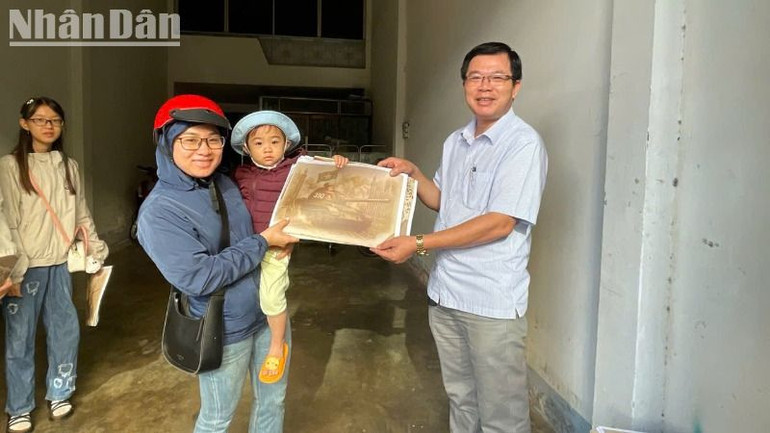 Một phụ nữ bế con nhỏ cũng tranh thủ đến Văn phòng đại diện Báo Nhân Dân tại Đắk Lắk để nhận phụ san đặc biệt.