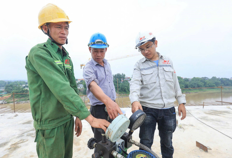 Kỹ sư, công nhân Công ty 99 (Tổng Công ty Xây dựng Trường Sơn) đo đạc, kiểm tra độ chính xác các hạng mục cầu Phong Châu.