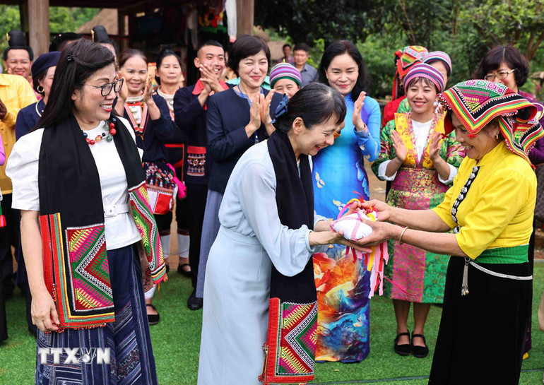 Nghệ nhân Lò Thị Tóm đại diện nhóm đồng bào Thái tặng bà Lê Thị Bích Trân, Phu nhân Thủ tướng Phạm Minh Chính và bà Ishiba Yoshiko, Phu nhân Thủ tướng Nhật Bản khăn Piêu và quả còn. Ảnh: MNH ĐỨC/TTXVN